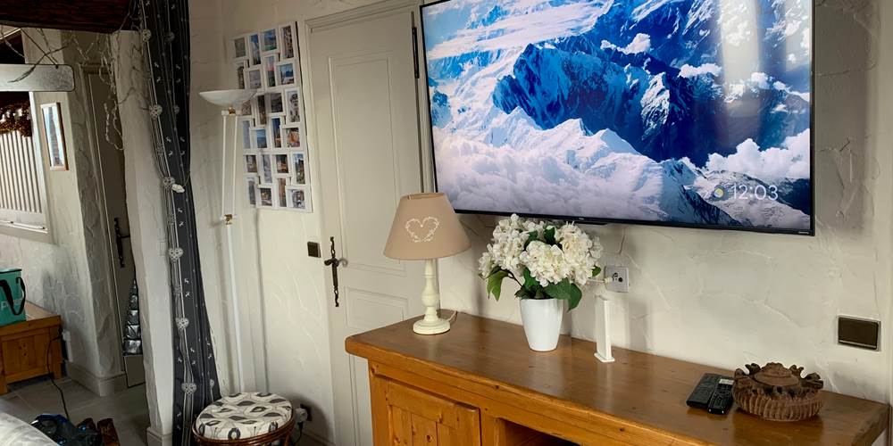 Télévision dans le salon avec à gauche porte du cabinet de toilettes