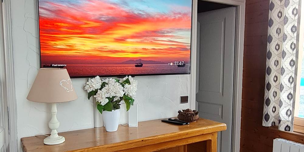 Télévision dans le salon avec à droite porte de la chambre
