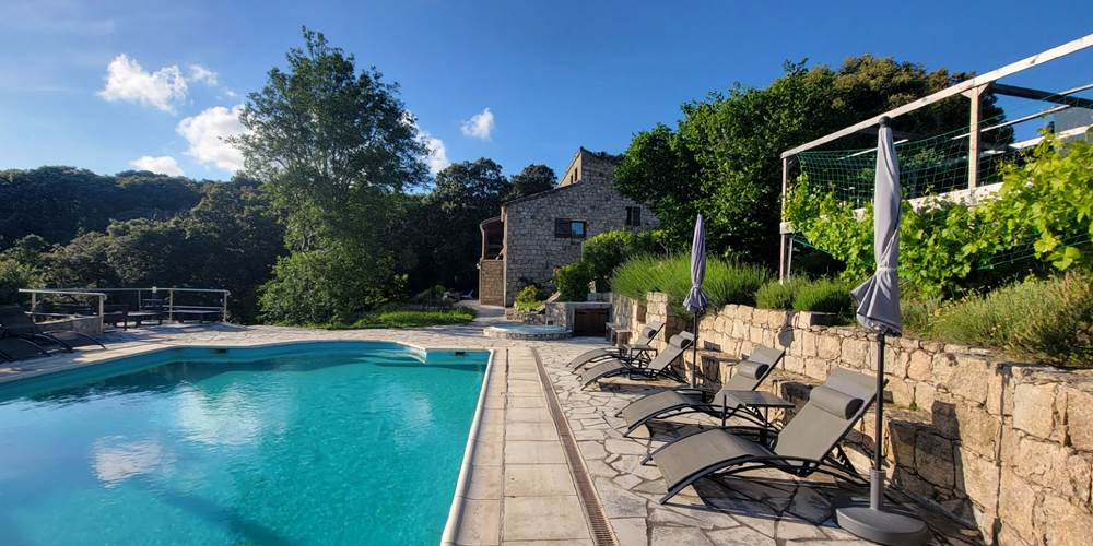Espace détente avec transats modernes au bord de la piscine avec vue sur les montagnes.