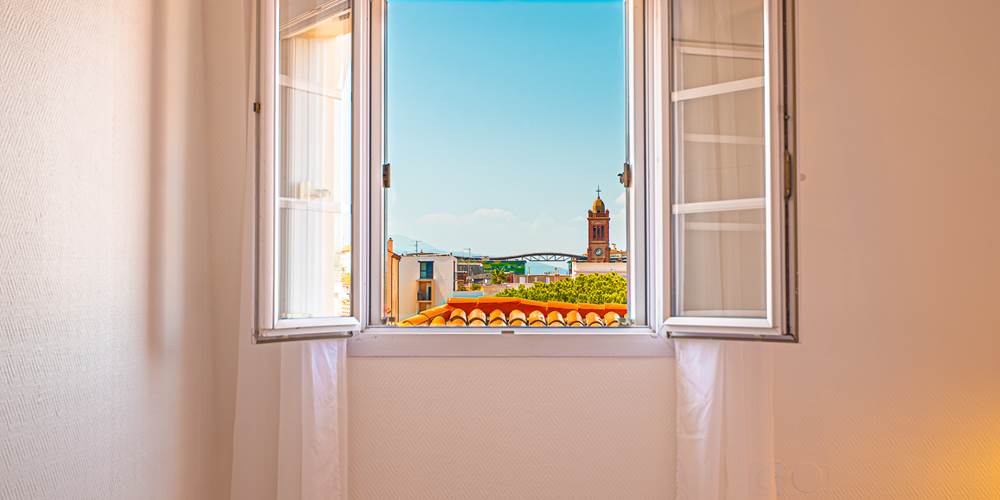 Une fenêtre comme un tableau pour admirer les toits de la ville et la lumière dorée du Sud.