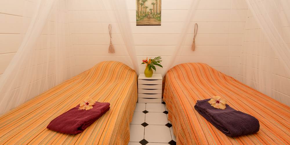 Deuxième chambre du gîte Ylang 1, lit double avec drapés, location saisonnière L'Étang-Salé La Réunion