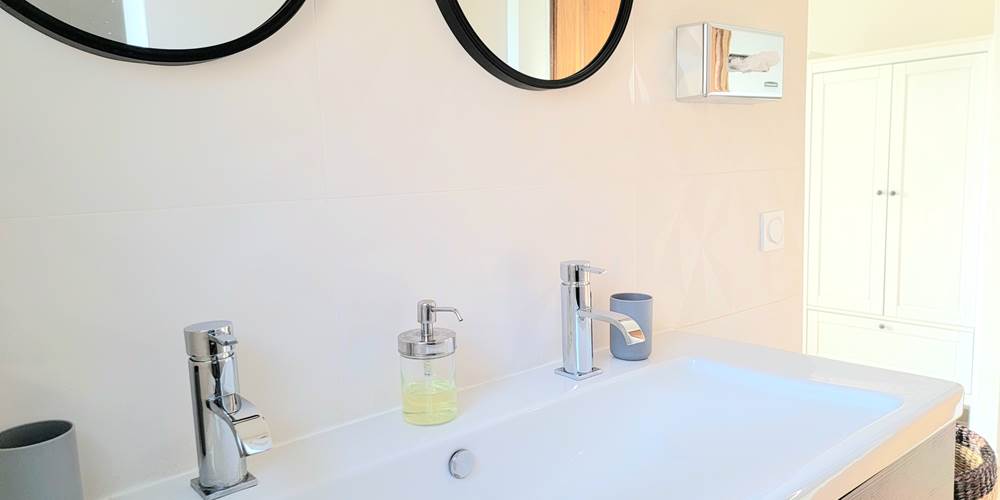 Salle de bain moderne et épurée avec double vasque, équipements de qualité au domaine.