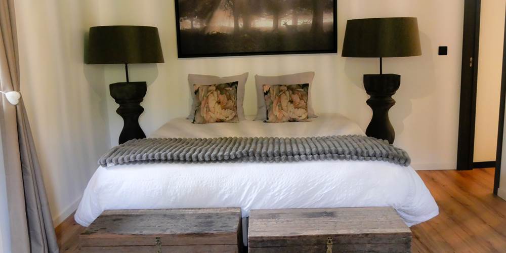 Une belle chambre à l’étage avec lit king size, coin détente et imposante lampe de chevet qui apporte une touche de caractère et une ambiance chaleureuse, idéale pour des nuits tout en douceur.