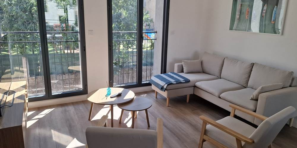 Salon confortable du gîte Le Pressoir avec vue sur la terrasse, au cœur de Montblanc.