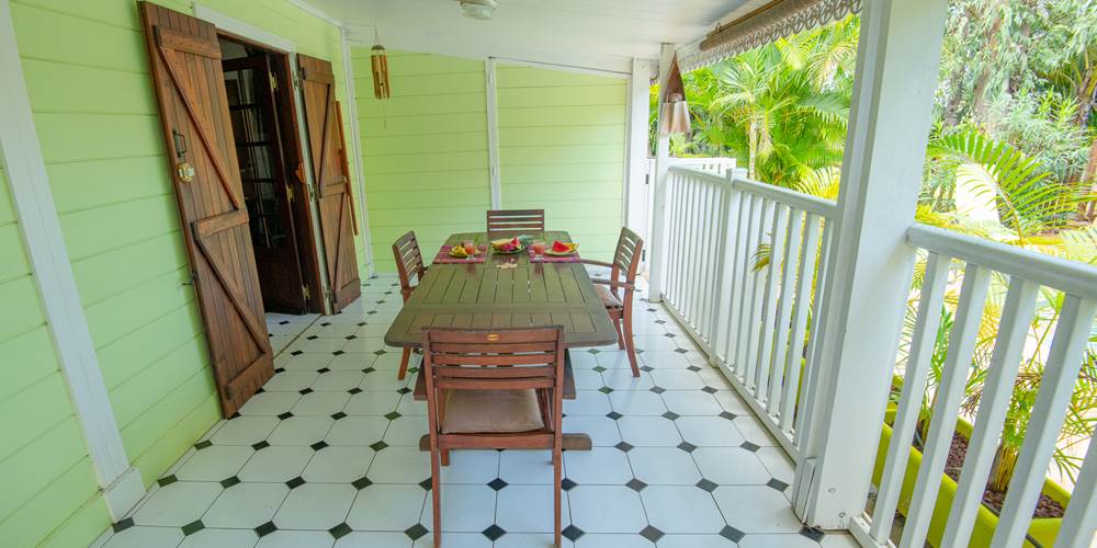 Terrasse couverte du gîte Ylang 1 avec vue directe sur la piscine, varangue créole à Baobab et Palmiers