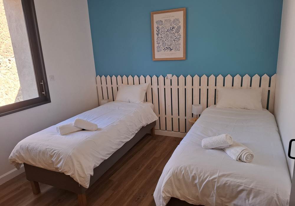 Chambre avec deux lits simples du gîte Le Pressoir à Montblanc, idéale pour enfants ou amis.
