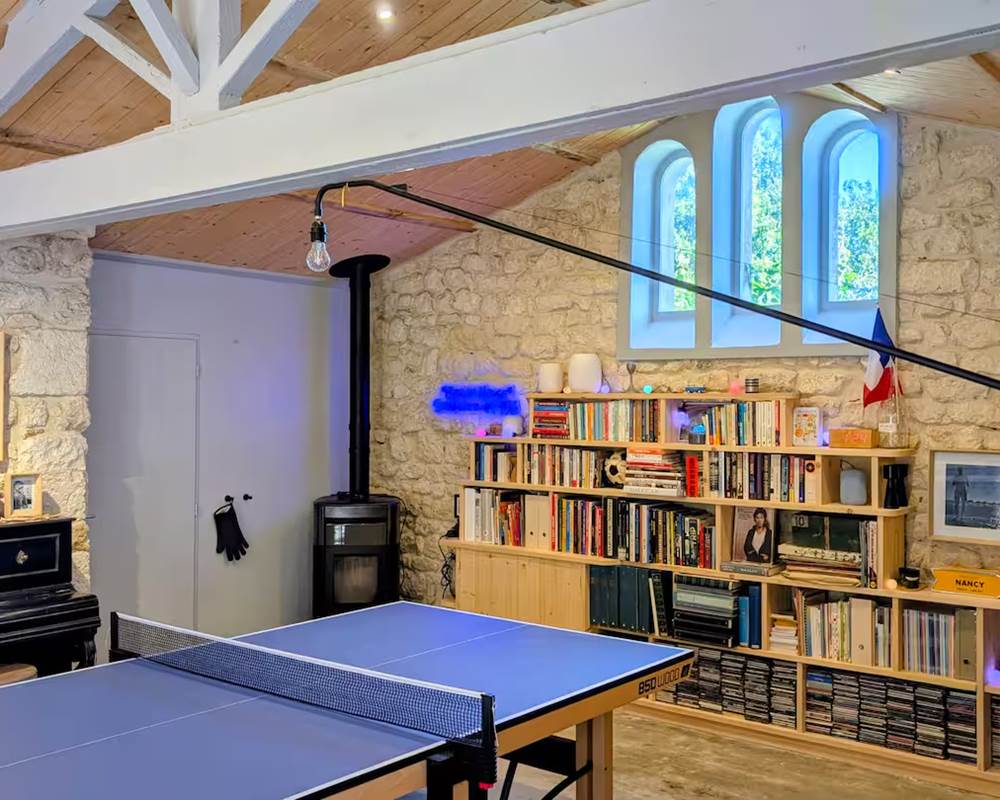 Salle de jeux avec baby-foot, ping-pong, bibliothèque et poêle à granulés