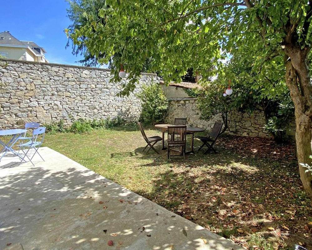 Terrasse du gîte avec tables extérieures et verdue
