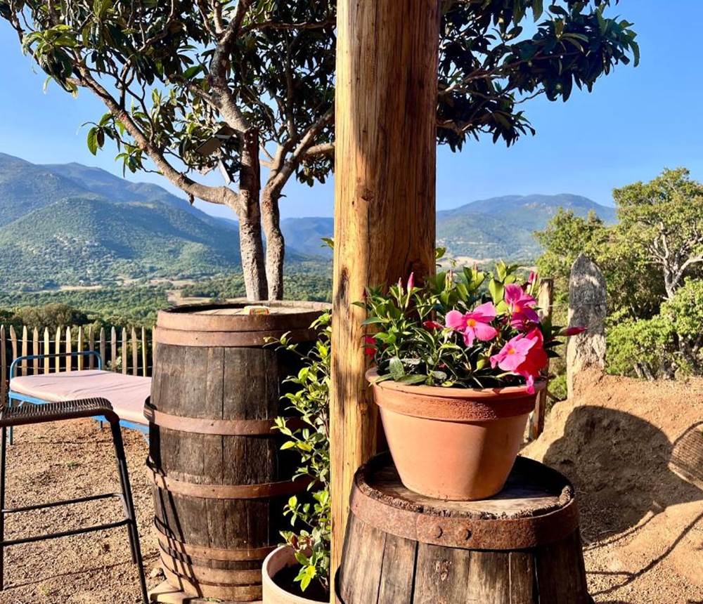 Coin apéro avec tonneau et vue imprenable sur les montagnes.