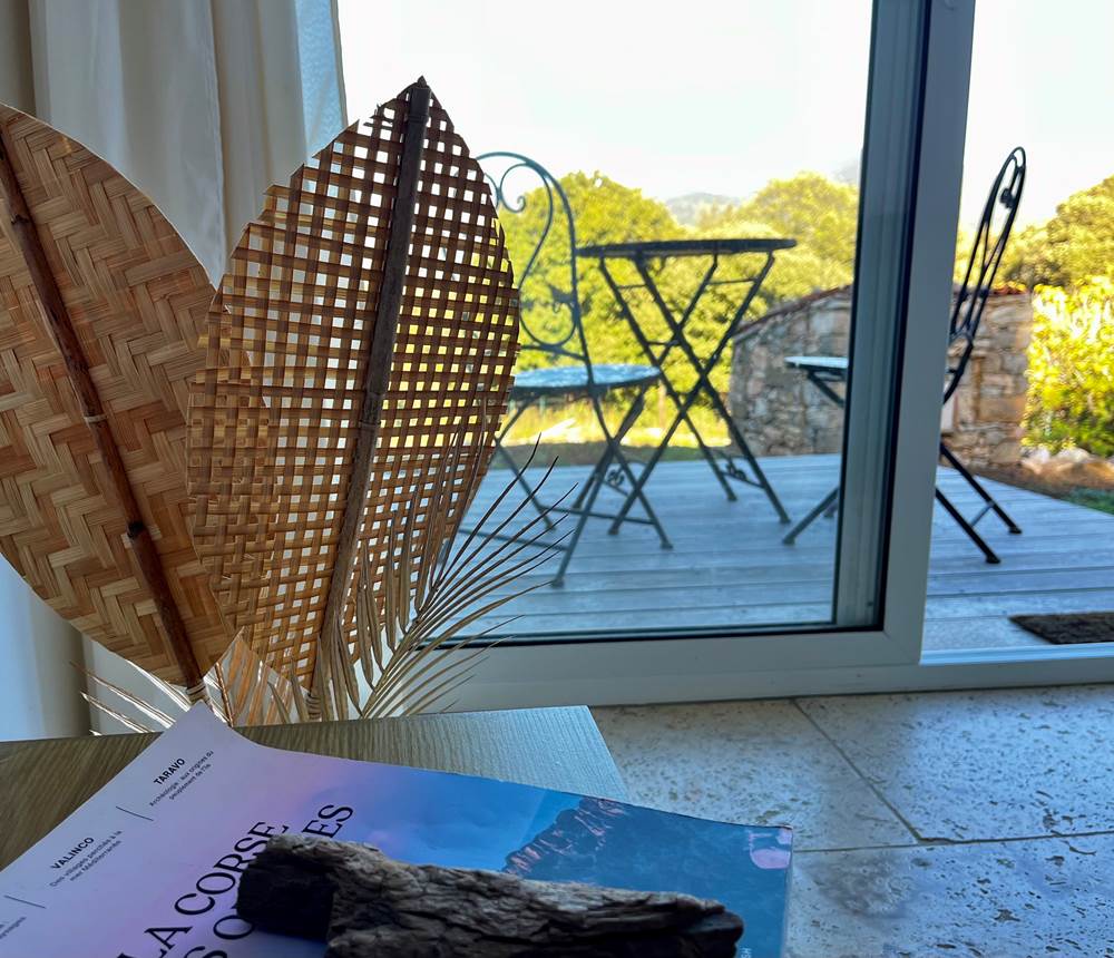 Terrasse ensoleillée avec table bistro, idéale pour un café face à la nature.
