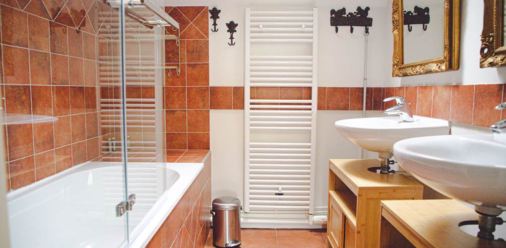 Laissez-vous séduire par cette salle de bain lumineuse, où une fenêtre de toit inonde l'espace de lumière naturelle, tandis qu'une baignoire et un double vasque vous invitent à la détente
