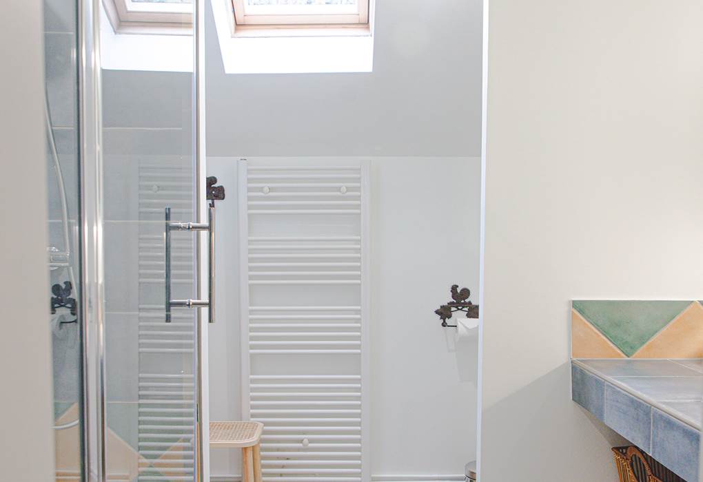 Salle de bains baignée de lumière naturelle grâce à sa fenêtre de toit, offrant un espace fonctionnel et aéré.