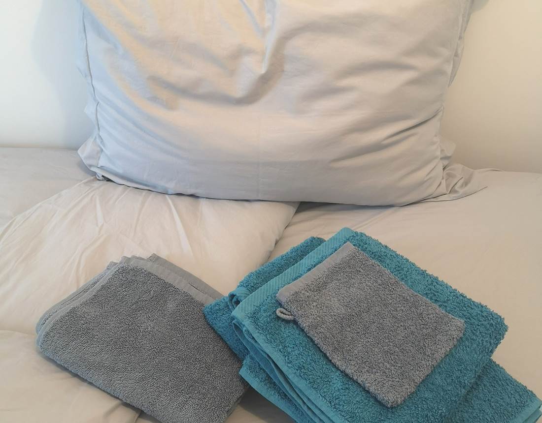 Linge de maison composé de draps de lit, housse de couette, taie d'oreillers, serviette de bain et tapis de douche.