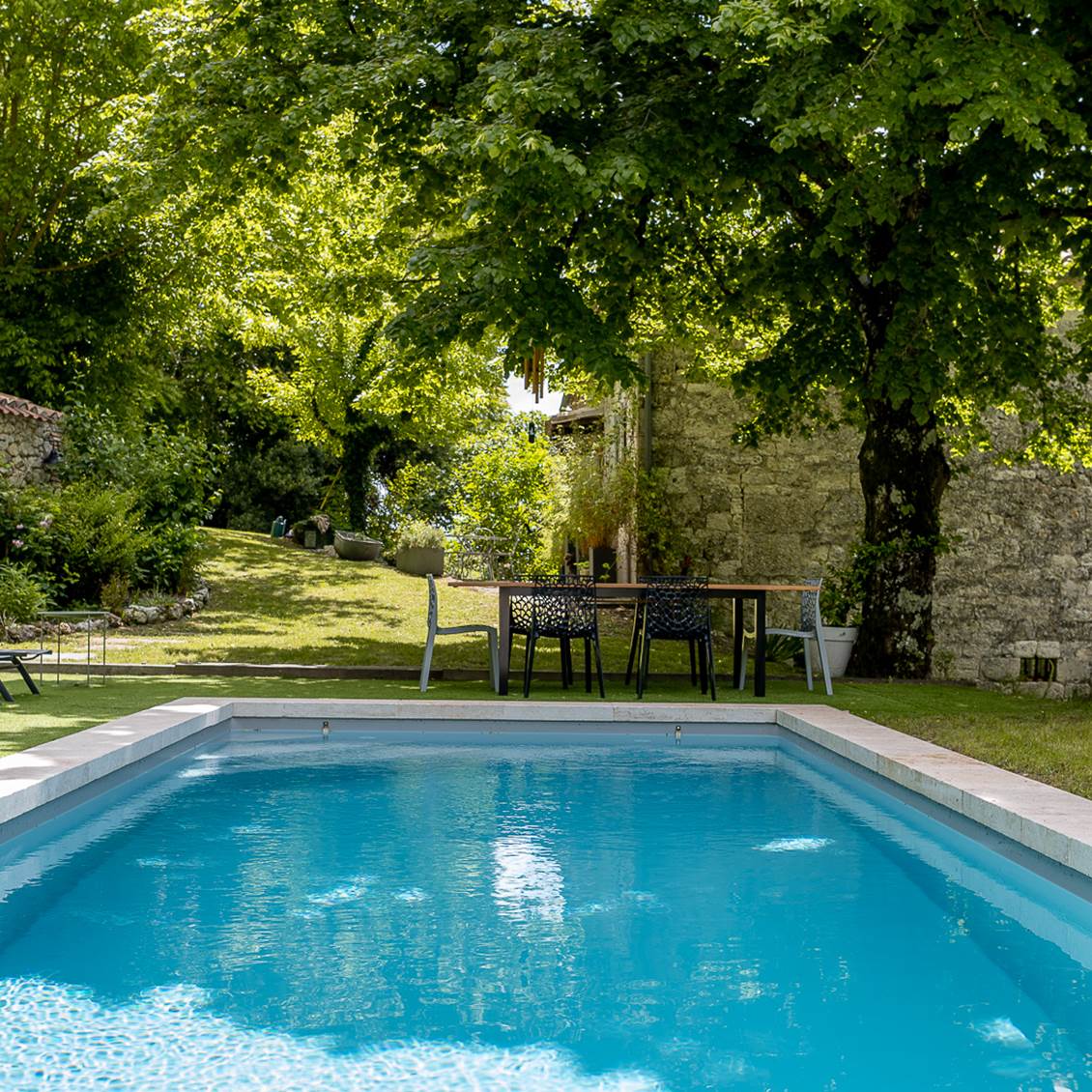 Table extérieure avec vue sur la piscine et le jardin arboré