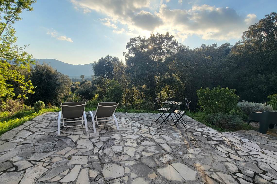 Terrasse en pierre avec transats privatifs offrant une vue panoramique sur les montagnes
