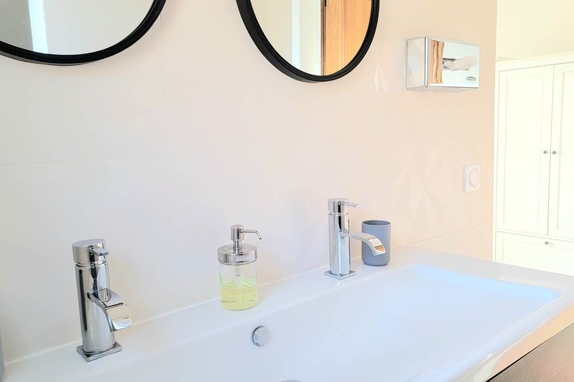 Équipements de salle de bain haut de gamme avec double vasque et miroir rond.