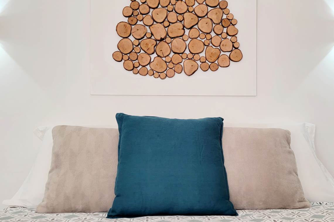 Décoration artisanale réalisée avec une branche du jardin du domaine, installée au-dessus d'un lit douillet dans la chambre d'amis 3.