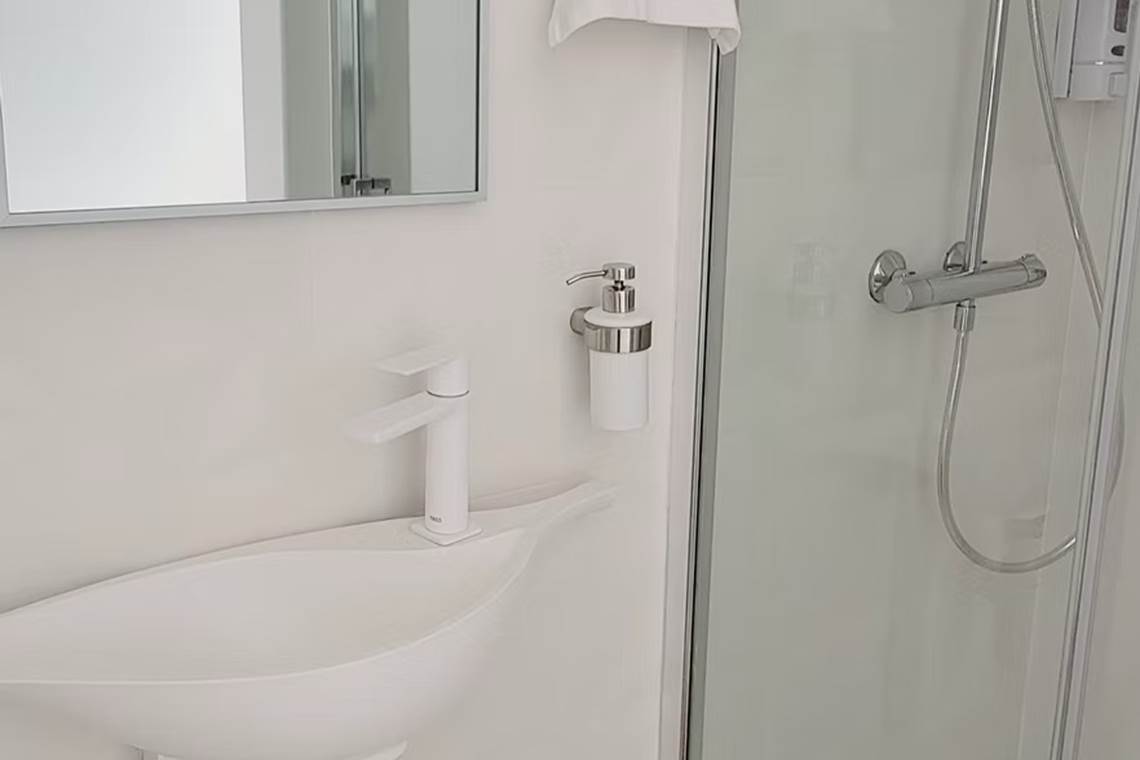 Salle d'eau fonctionnelle avec douche à l'italienne et petit lavabo.