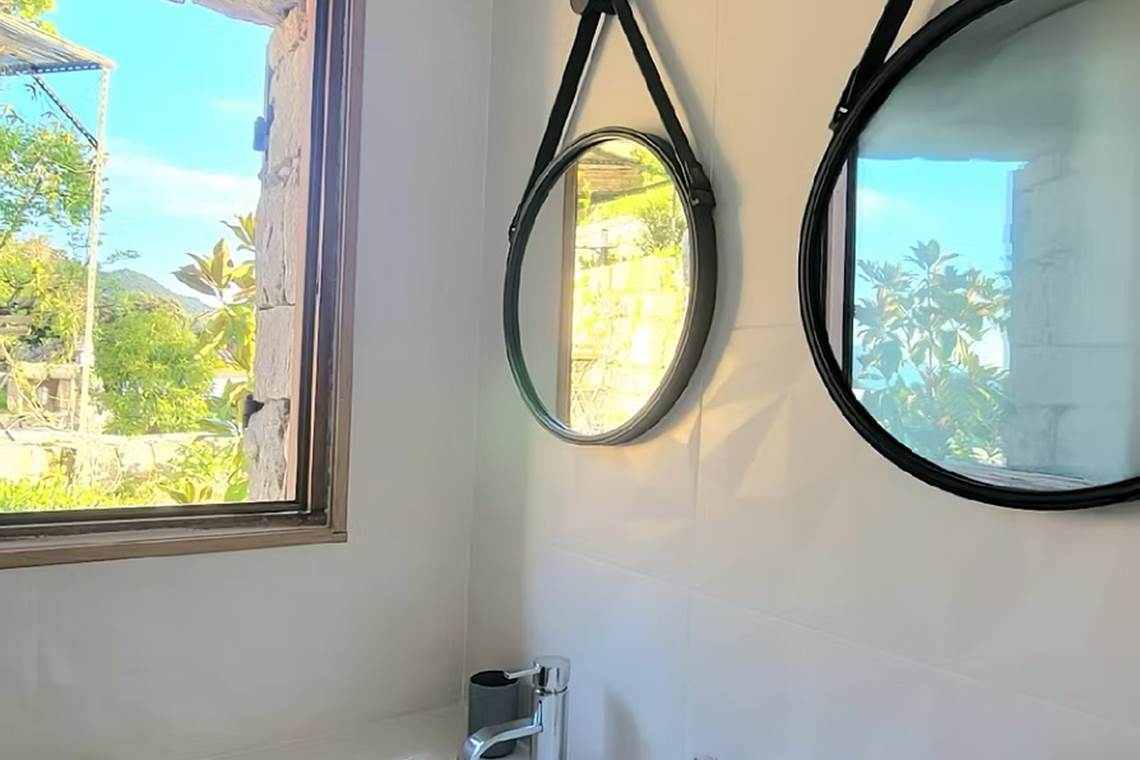 Salle d'eau lumineuse avec vue sur le jardin et miroirs design pour un confort moderne.