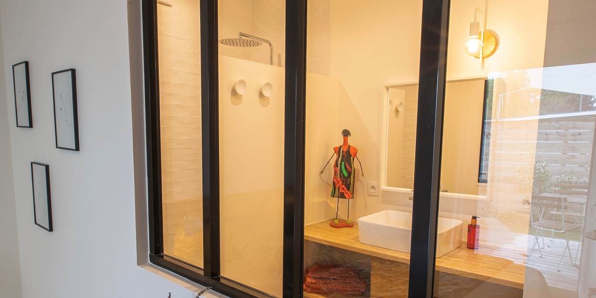 La verrière qui sépare la chambre de la salle de bain donne une touche de modernité à la déco