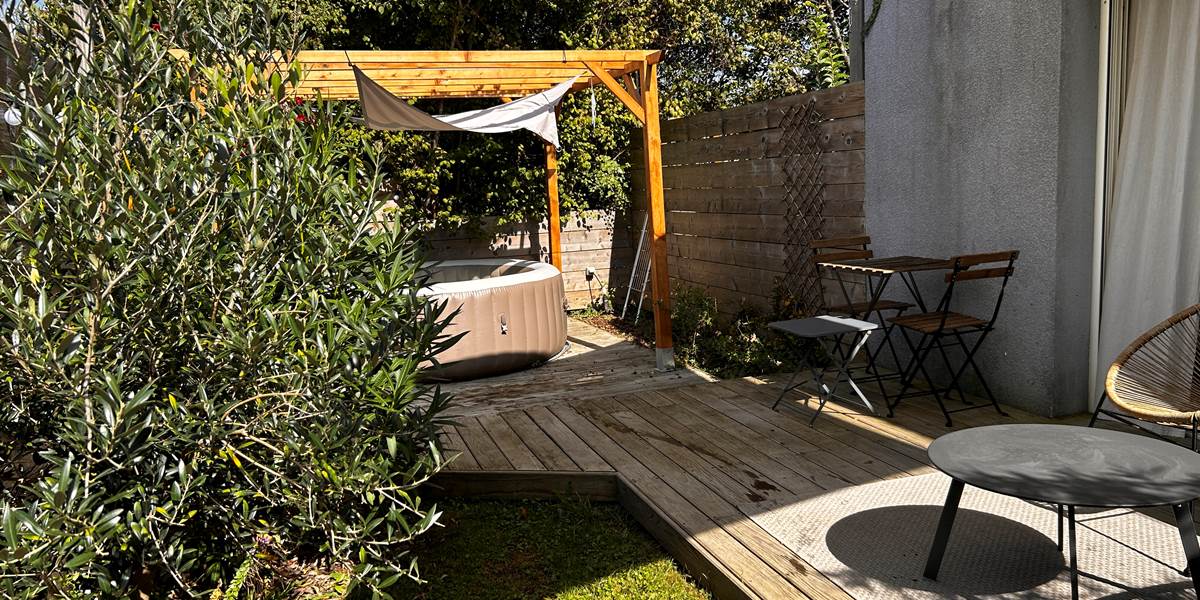 le spa privatif  sous la pergola de la chambre Essentielle, entouré de verdure . Un cadre idéal pour se relaxer et se ressourcer en pleine nature.