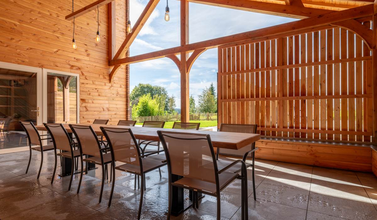 Terrasse couverte avec table en bois pour 10 personnes.