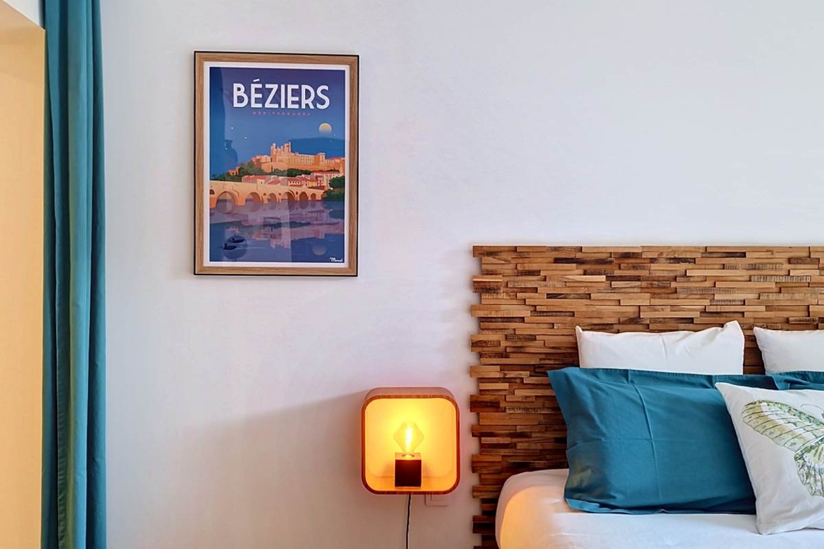 Décoration de la Chambre Bleue avec tête de lit en bois et affiche de Béziers