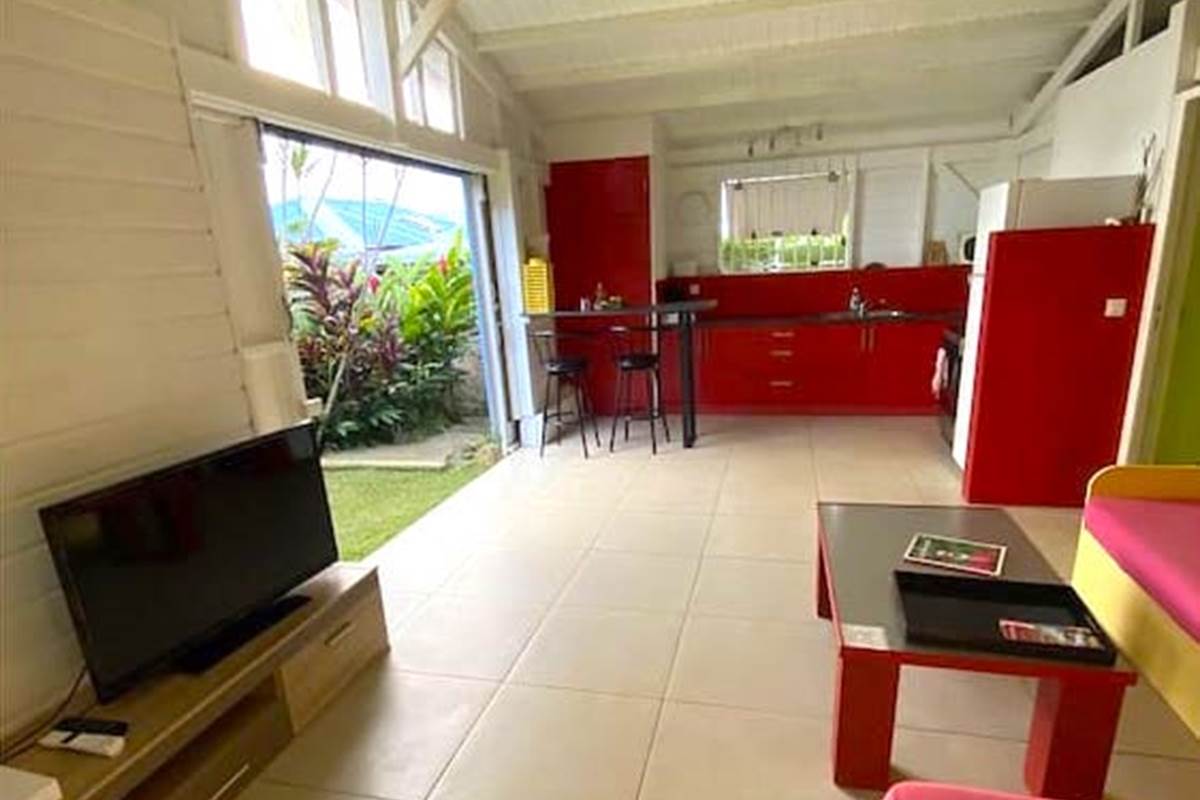 Séjour vers la cuisine avec grande ouverture sur le jardin