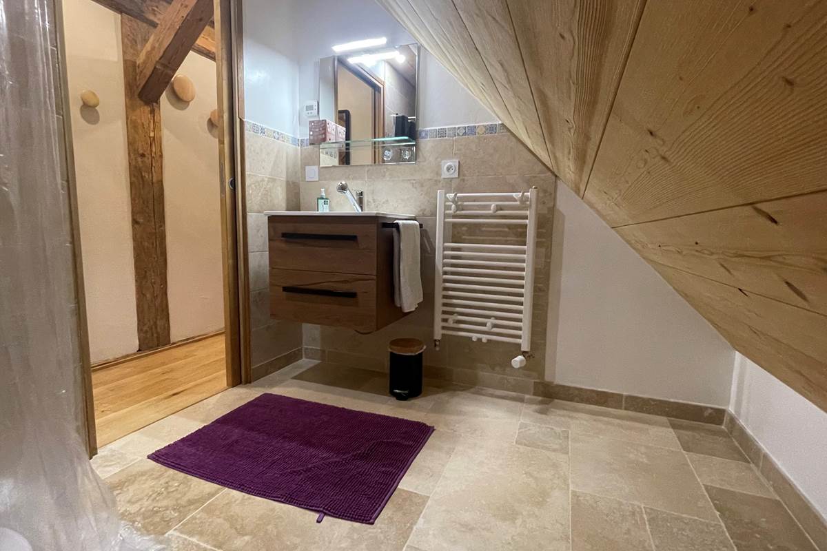 Salle de bain avec lavabo, douchette, sèche serviette et sèche cheveux.