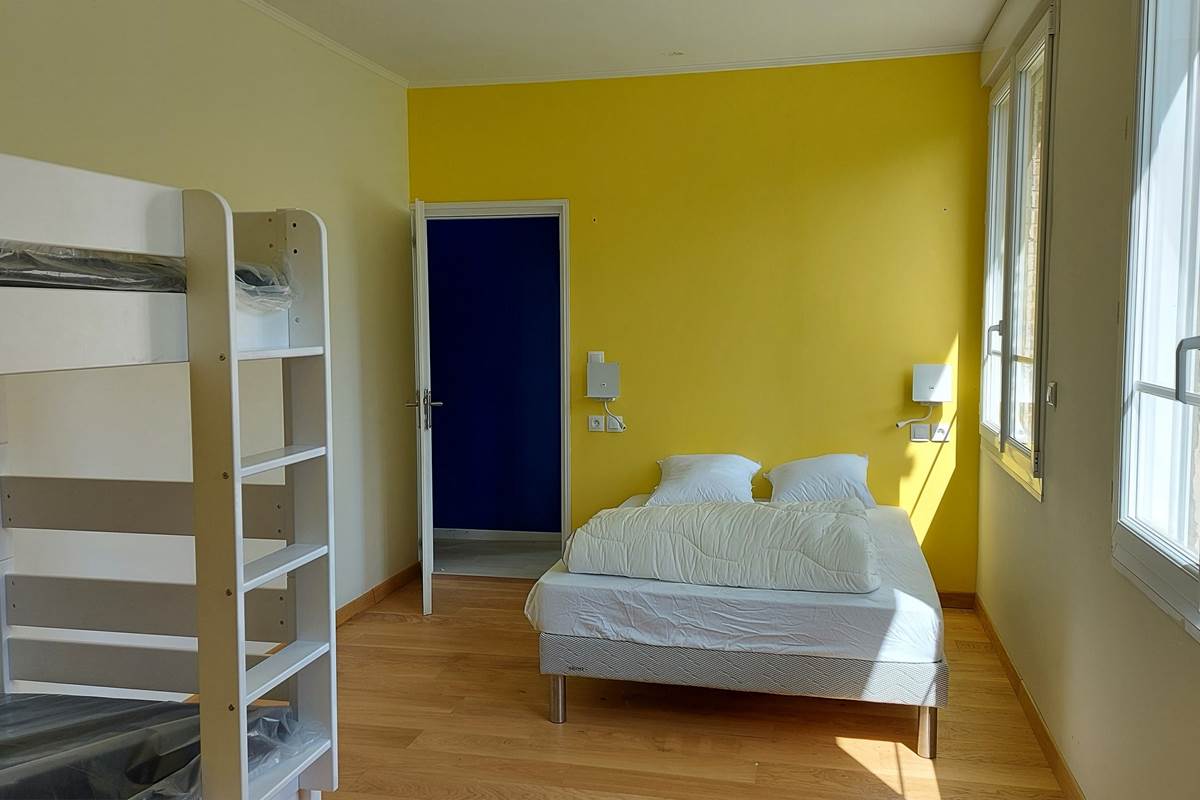 Chambre jaune lumineuse avec lit double 140x200 et lit superposé, idéale pour une famille avec enfants dans notre gîte du Pas-de-Calais.