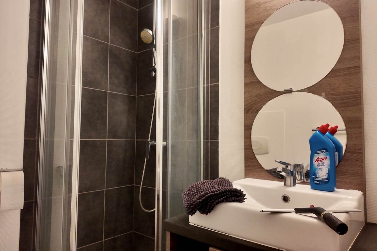 Salle de bain avec tapis de bain et produits de nettoyage
