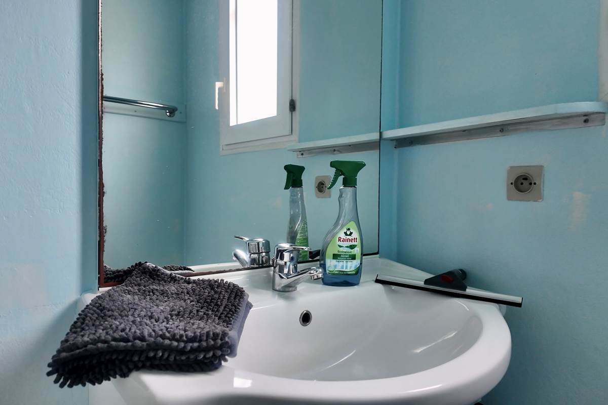 Salle de bain avec tapis de bain et produits de nettoyage