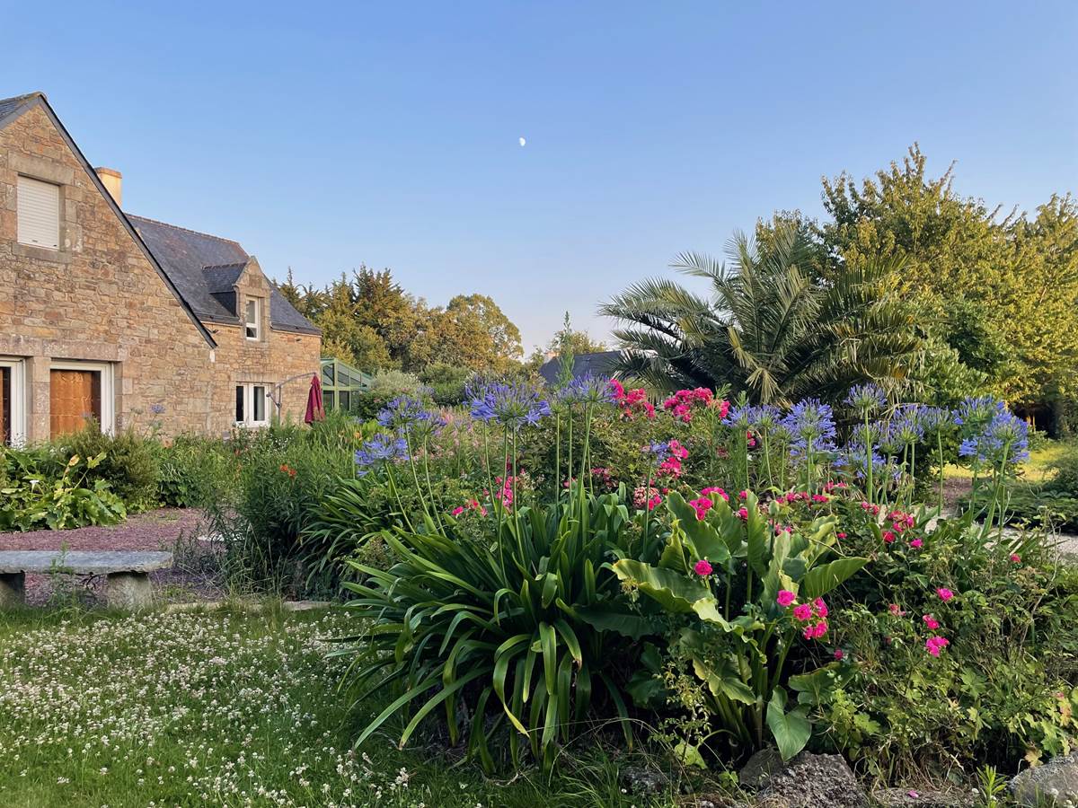 Maison entourée de massifs de fleurs (roses et agapenthes ici)