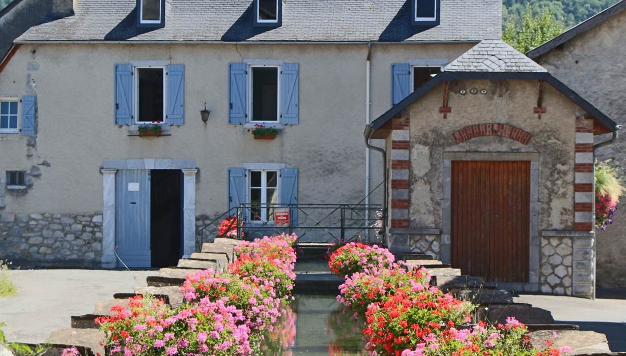 Gîte du Moulin : Le canal fleuri et la façade du moulin.