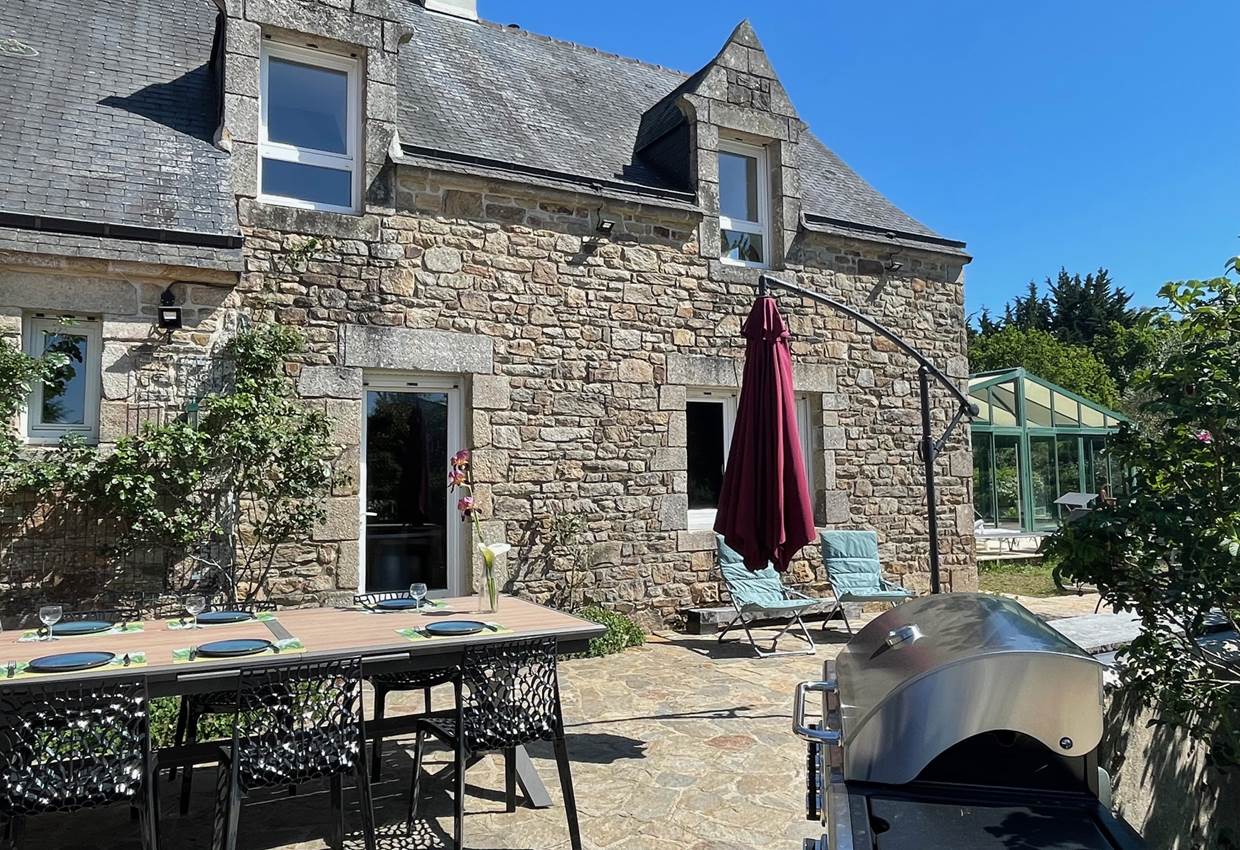 Facade maison avec table mise pour 6 et barbecue