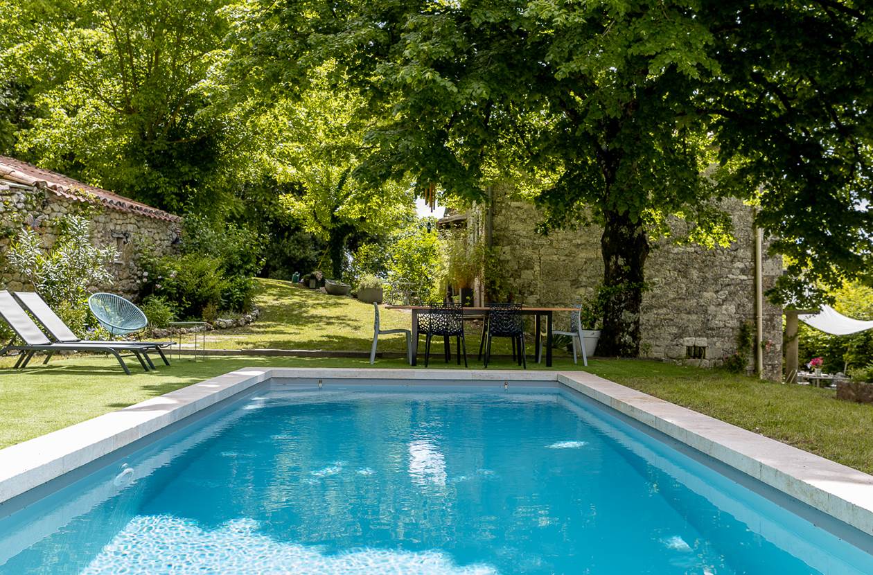 Table extérieure avec vue sur la piscine et le jardin arboré