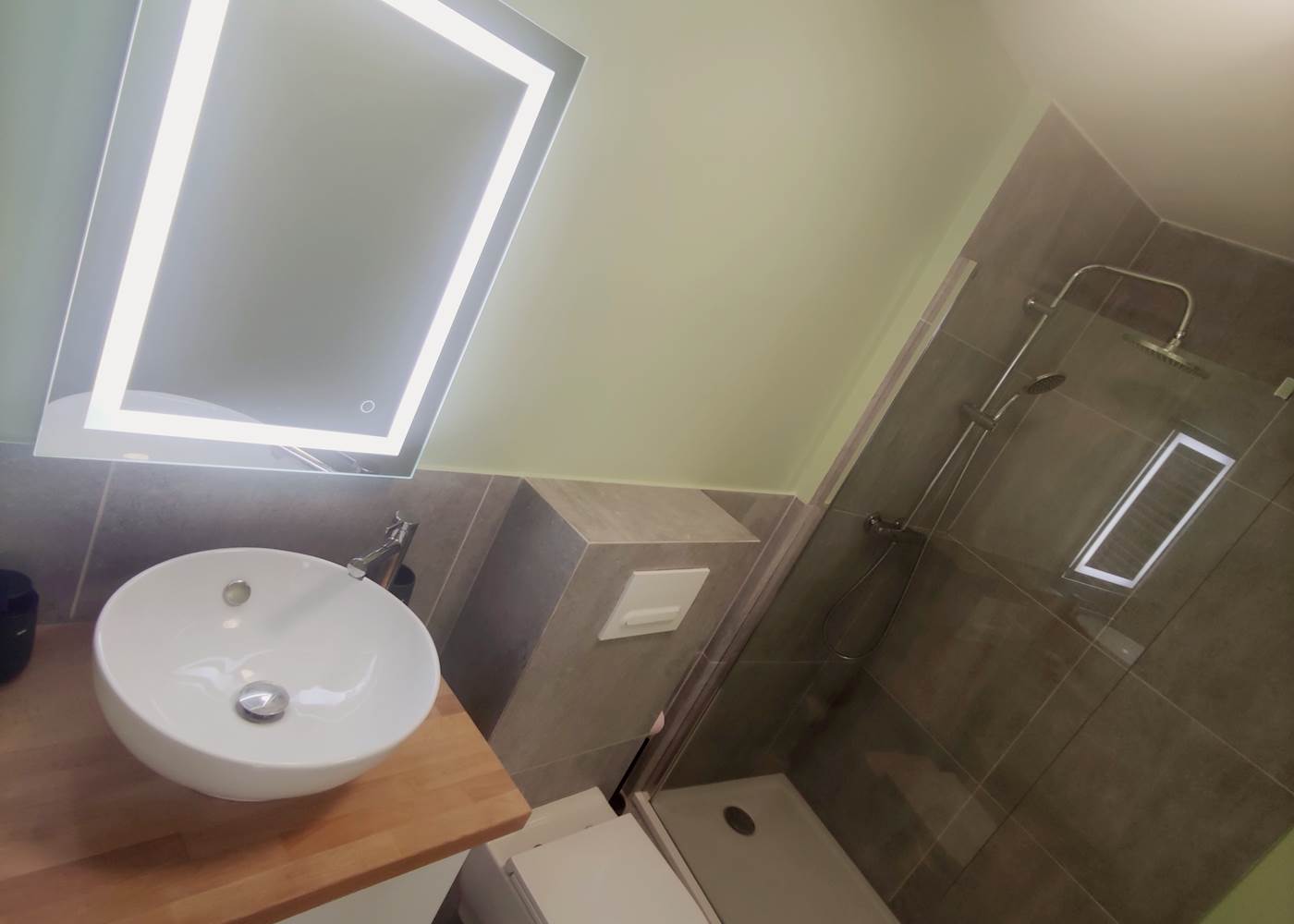 Salle d’eau contemporaine dans un esprit épuré Miroir rétroéclairé, vasque élégante et douche italienne : un espace bien pensé pour votre confort quotidien.