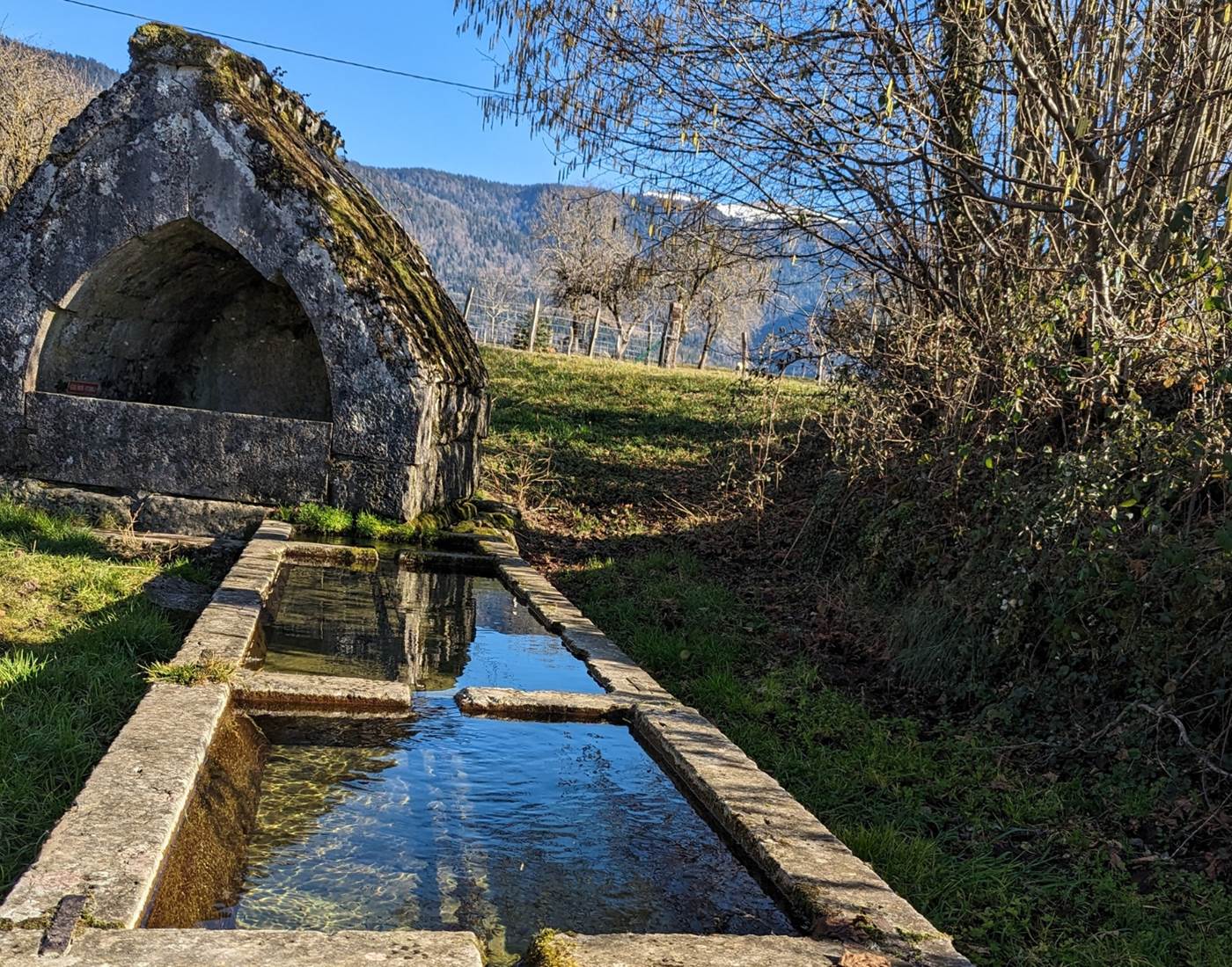 Découvrez le lavoir médiéval de Poisieu, un vestige authentique dans le Bugey. Ce lavoir offre une vue imprenable sur le  Grand Colombier. Un lieu paisible où nature et patrimoine se rencontrent.