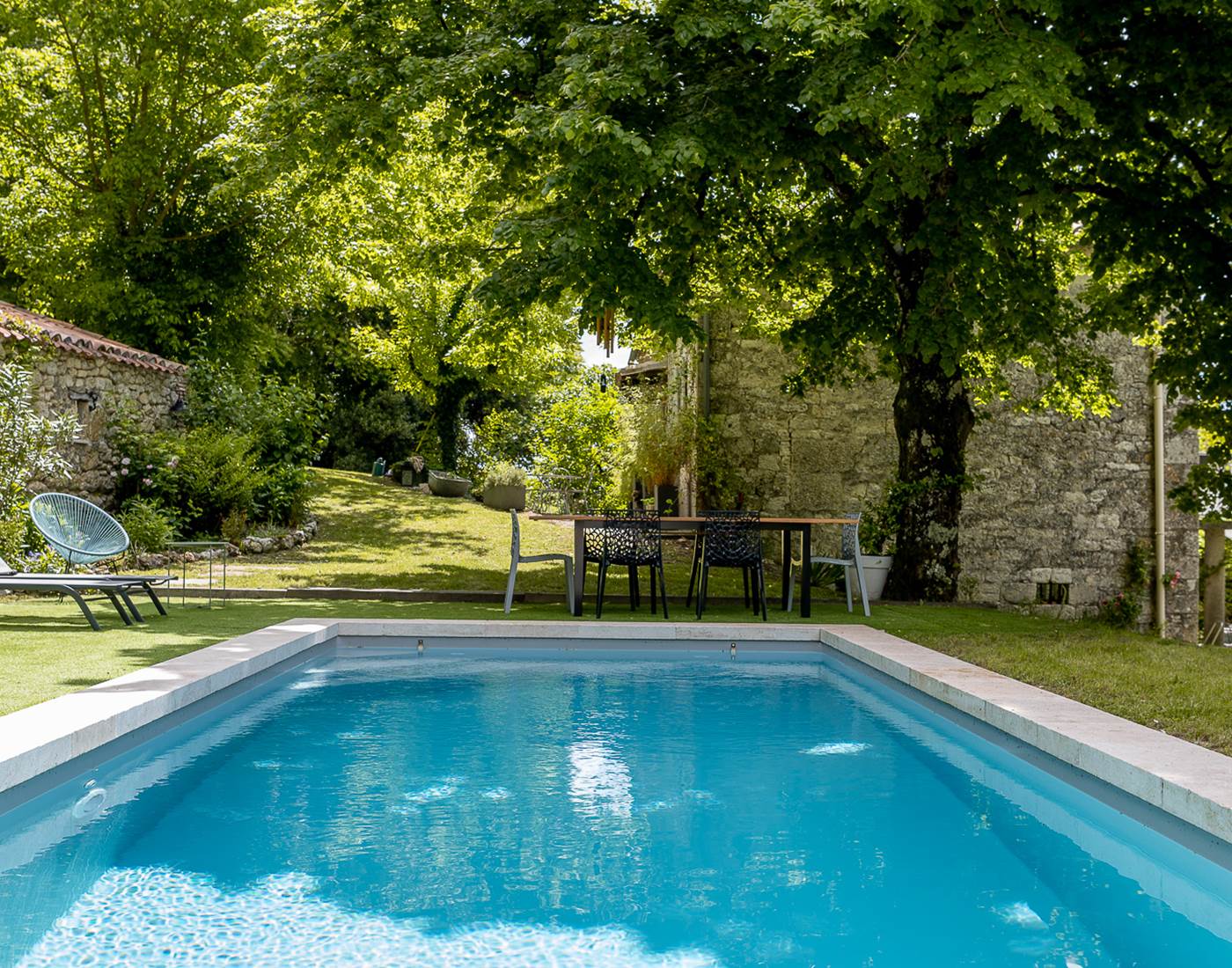 Table extérieure avec vue sur la piscine et le jardin arboré