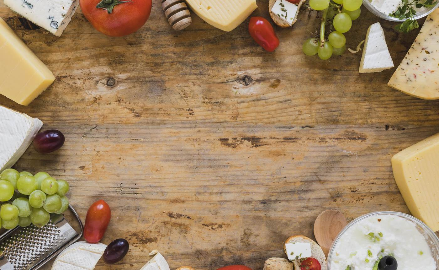 plateau-de-fromages-avec-tomates-raisins-et-mini-sandwichs-sur-un-bureau-en-bois-avec-espace-pour-ecrire-le-texte-min