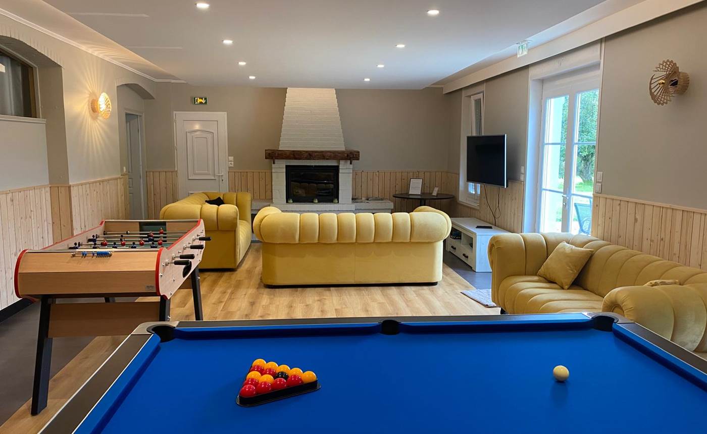 Espace détente lumineux avec cheminée, jeux et TV : tout le confort d’un gîte rural de charme en Hauts-de-France