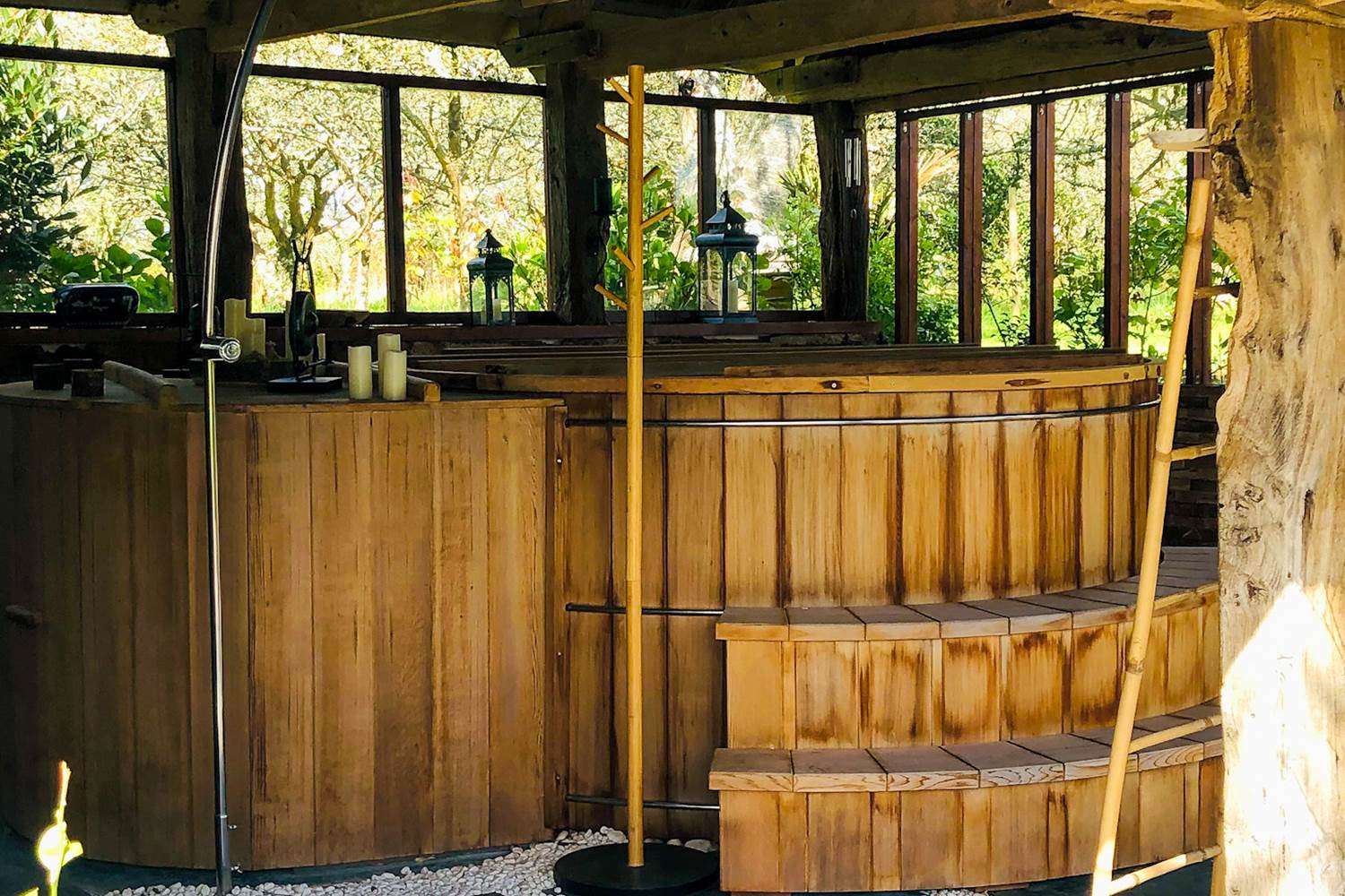 un grand bain en cèdre rouge abrité sous un joli préau