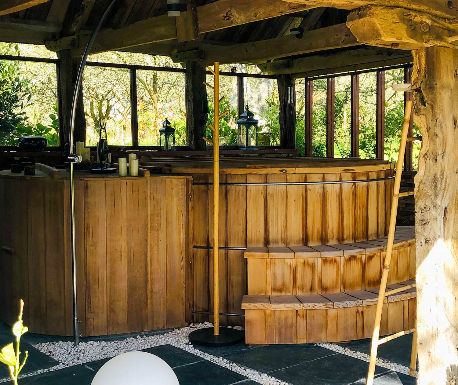 un grand bain en cèdre rouge abrité sous un joli préau