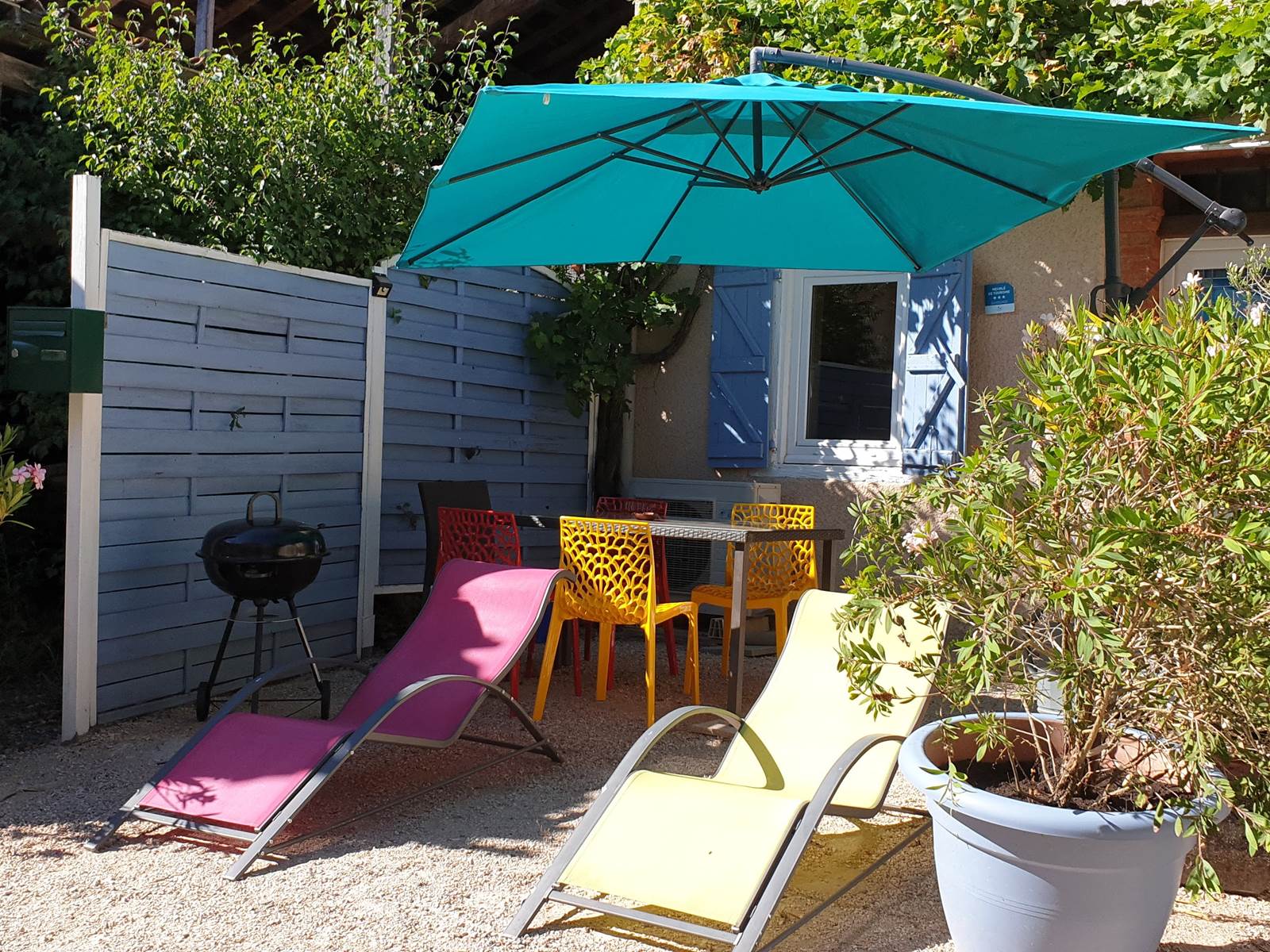 Terrasse devant le gîte, salon de jardin avec transats, parasol,  barbecue.