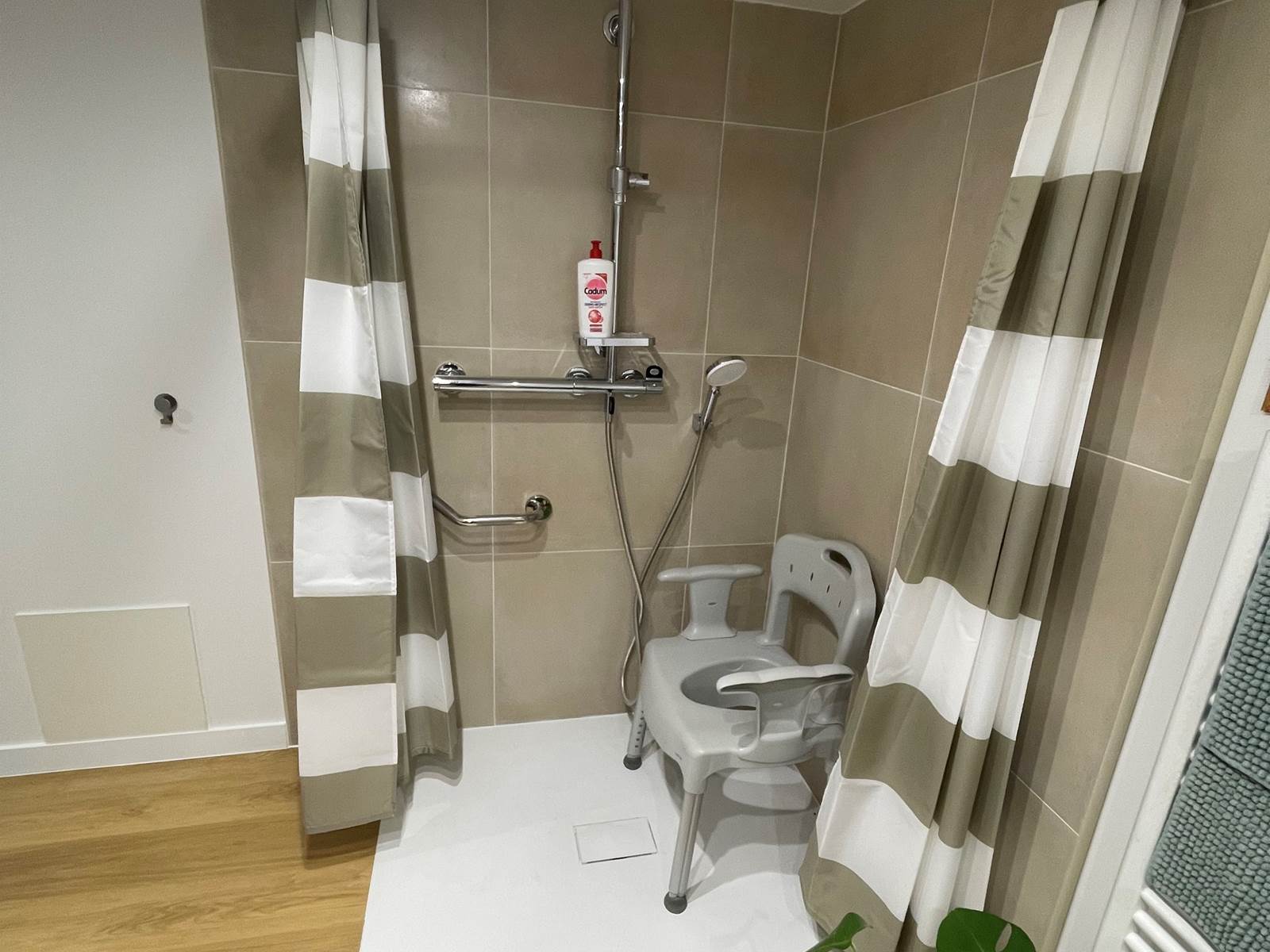Douche à l'italienne avec barre de maintien et chaise à disposition