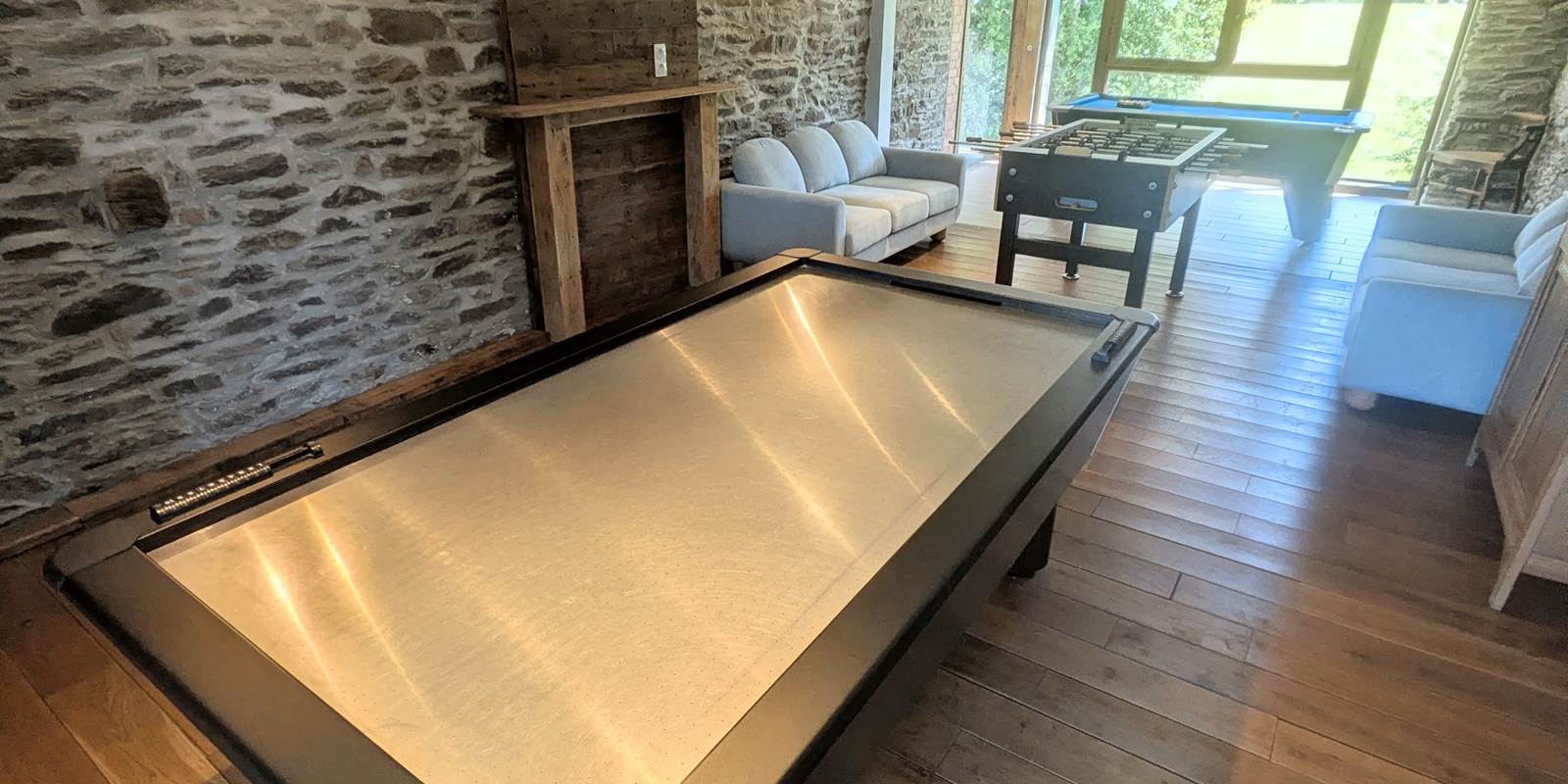 alt="Jeu de air hockey et fléchettes dans la salle de jeux du gîte familial en Belgique"