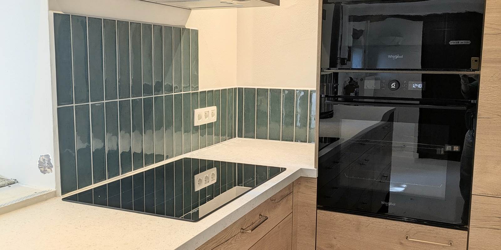 Coin cuisson moderne avec plaque à induction Whirlpool, four et micro-ondes dans la cuisine du gîte