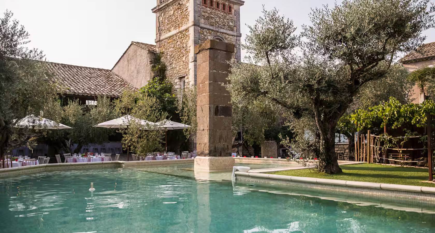 Grande piscine extérieure dans une cour fermée bordée d’oliviers centenaires