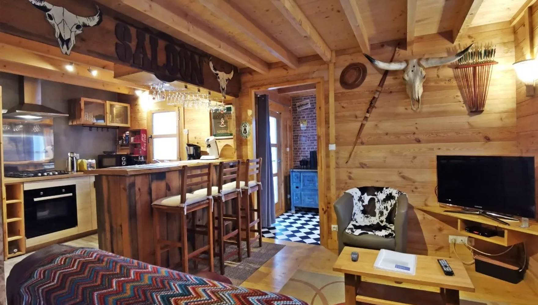 Salon chaleureux en bois avec télévision et bibliothèque, parfait pour un séjour cosy aux Chalets de Kerescar à Plouarzel