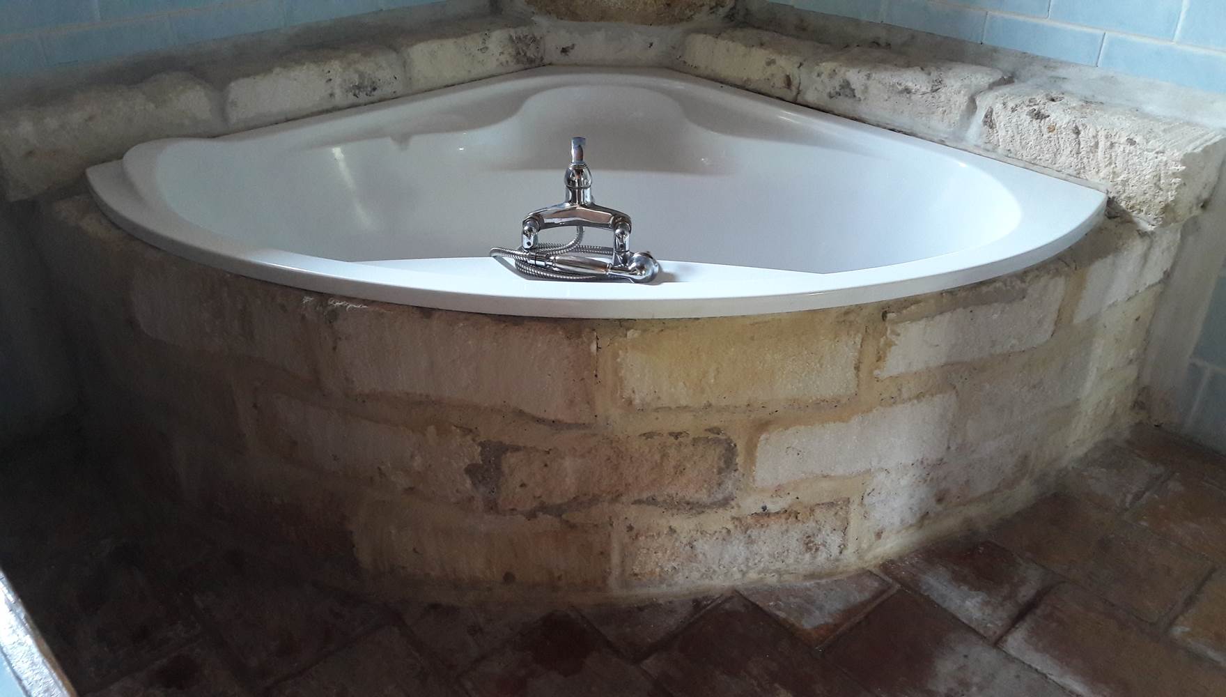 salle de bain avec baignoire d angle entouré de pierre de taille